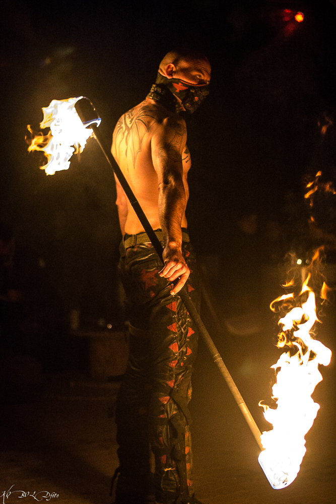 Eine Raubkrähe der Apokalyptiker macht mit Staubmaske, nacktem Oberkörper und einem an beiden Enden brennendem Feuerstab eine epische Figur.